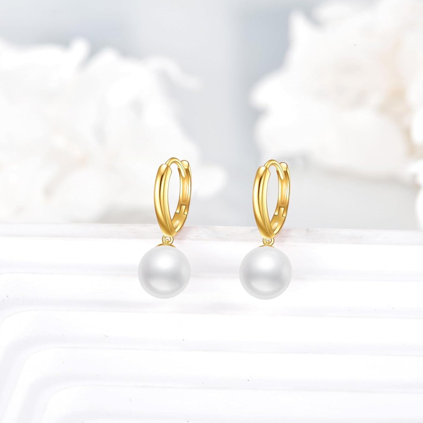 Pair of solid 14K gold pearl drop hoop earrings displayed on a pale background.