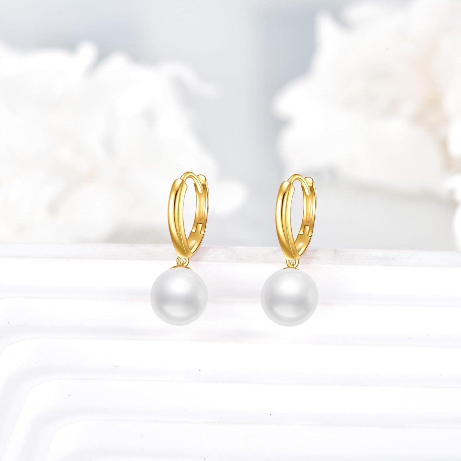 Pair of solid 14K gold pearl drop hoop earrings displayed on a pale background.