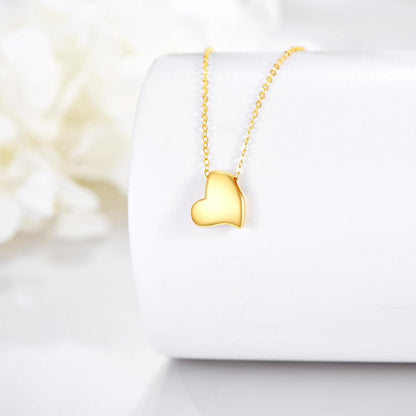 Asymmetric 14K yellow gold heart pendant necklace displayed on a white jewellery stand.