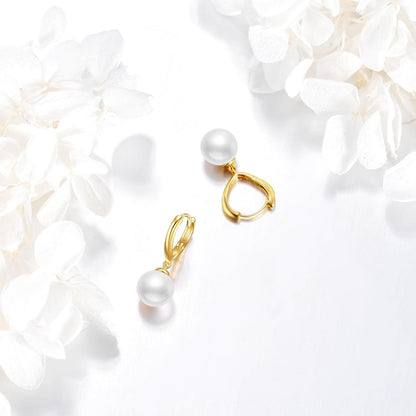 Solid 14K gold pearl drop hoop earrings styled with white flowers.